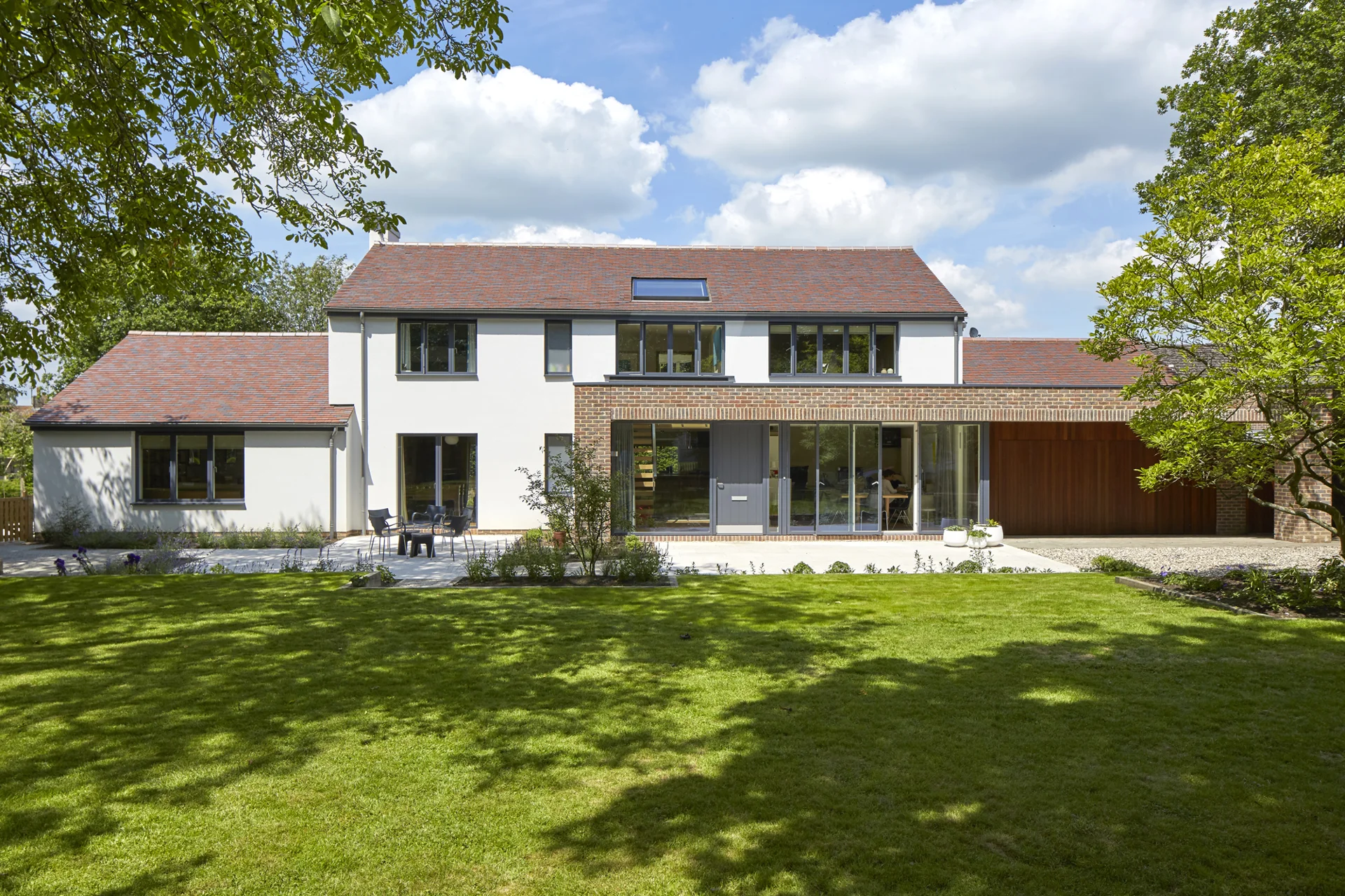 Witte woning met grote ramen aan een groene tuin